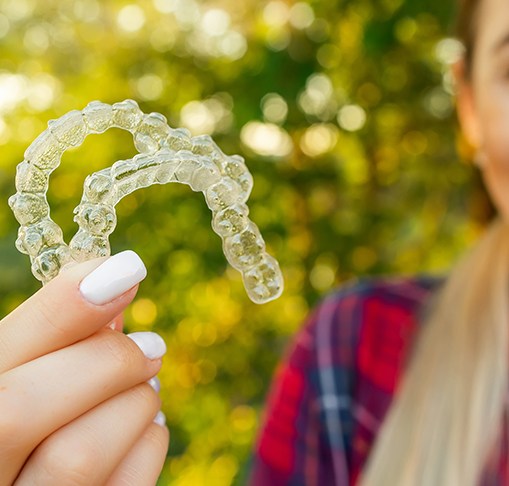 Patient in Gahanna smiling while holding clear aligners 