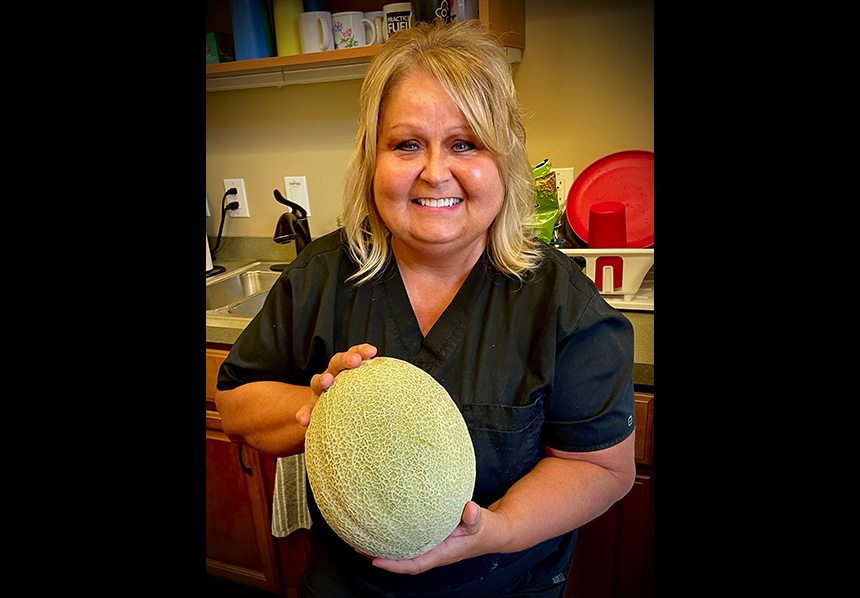 Dental team member holding a melon from the urban garden