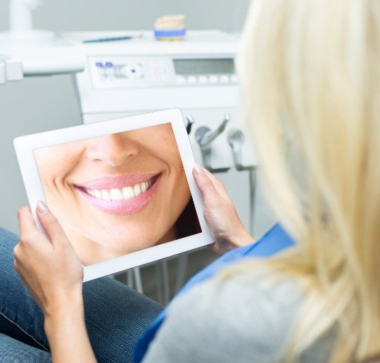 Woman looking at virtual smile design on tablet computer