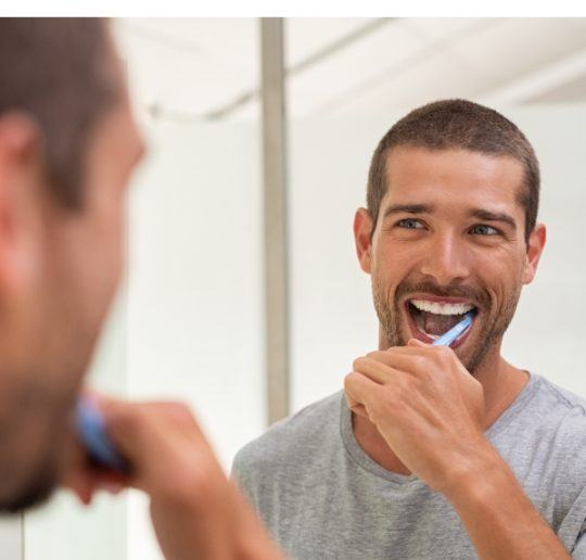 Man with dental crown and fixed bridge brushing teeth