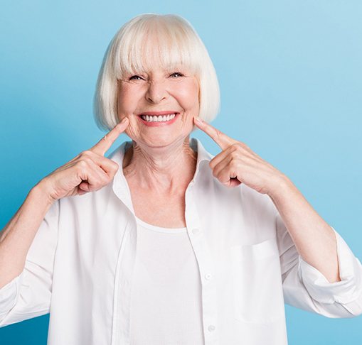 Woman smiling and pointing to her dentures