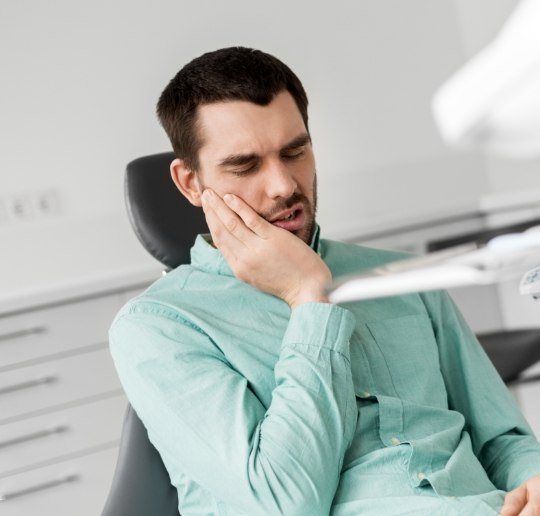 Man holding cheek in pain before emergency dentistry