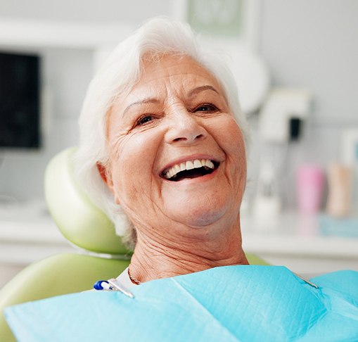 Senior woman leaning back in dental chair and laughing