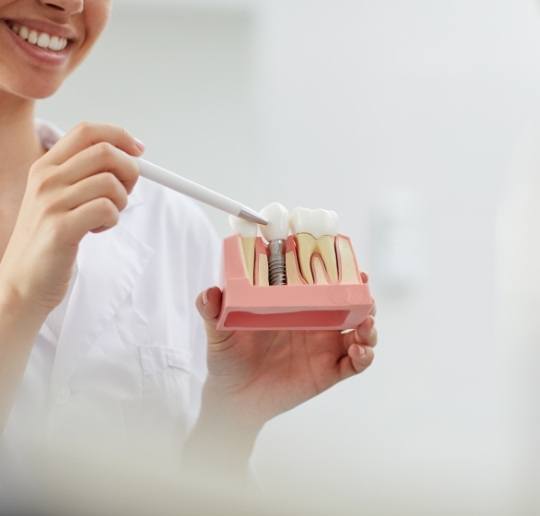 Dental team member pointing to dental implant supported dental crown