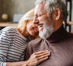 Man and woman smiling together after dental implant tooth replacement