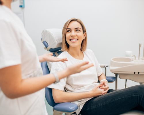 Smiling woman in dental chair talking to dentist