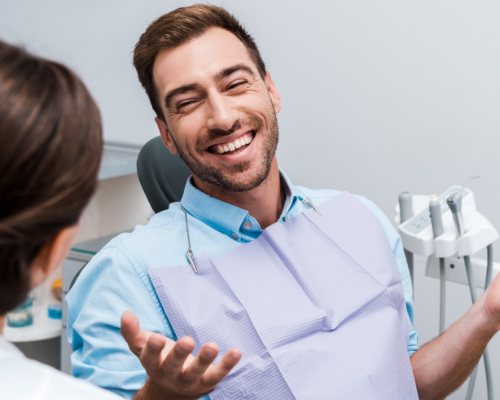 Man in dental chair smiling while talking to his dentist