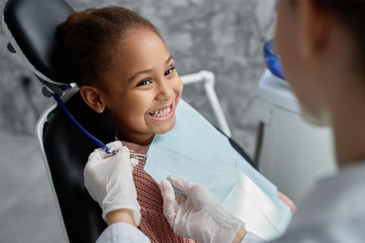 Child smiling happily in dental chair