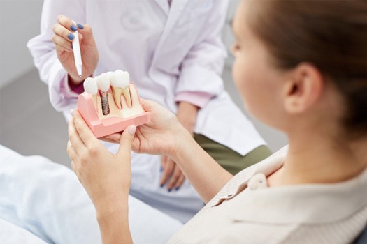 Patient looking at model of dental implant