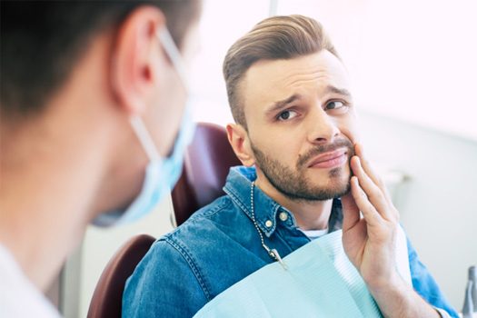 Patient holding cheek at emergency dental visit