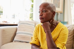 a woman in a yellow shirt sitting down and worried