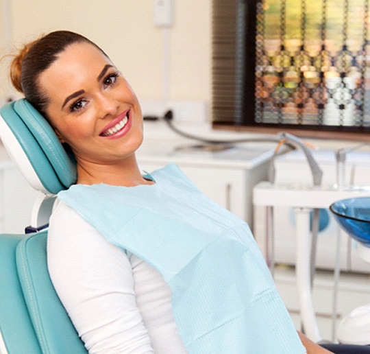 Woman smiling in dental chair after oral cancer screening in Gahanna, OH