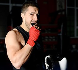 Man in gym putting mouthguard in before boxing