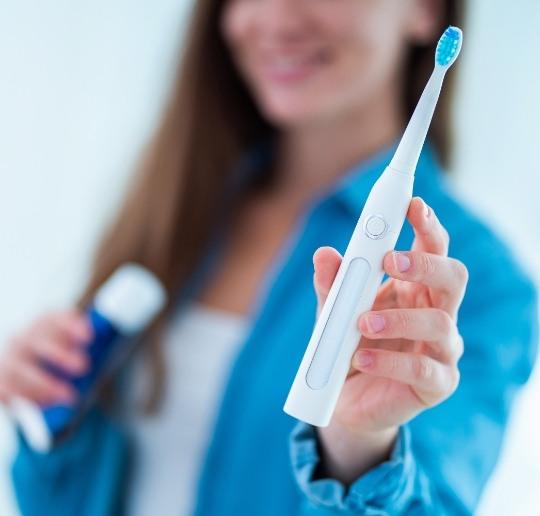 Woman using her toothpaste and electric toothbrush