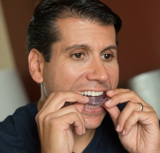 Man placing oral appliance to treat sleep apnea