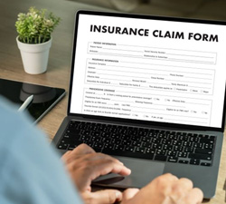 Person filling out insurance claim form on laptop