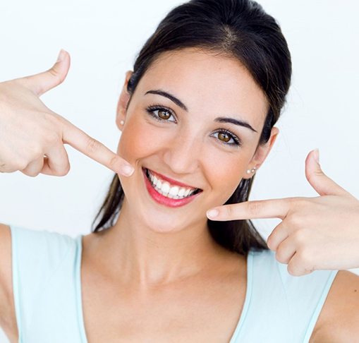 woman pointing to her smile after teeth whitening in Gahanna 