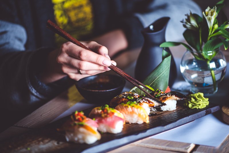 Pictures of people eating sushi with soy sauce.