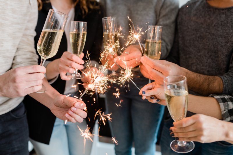 People holding sparklers and wine glasses on New Year’s Eve