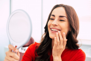 Woman admiring her shiny teeth in a small mirror