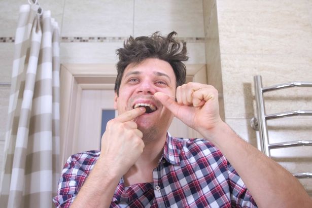 An unhappy man brushing his teeth