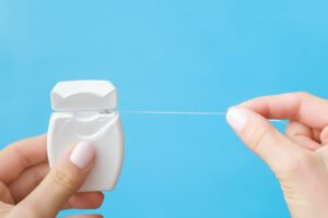 Hand pulling dental floss from case.